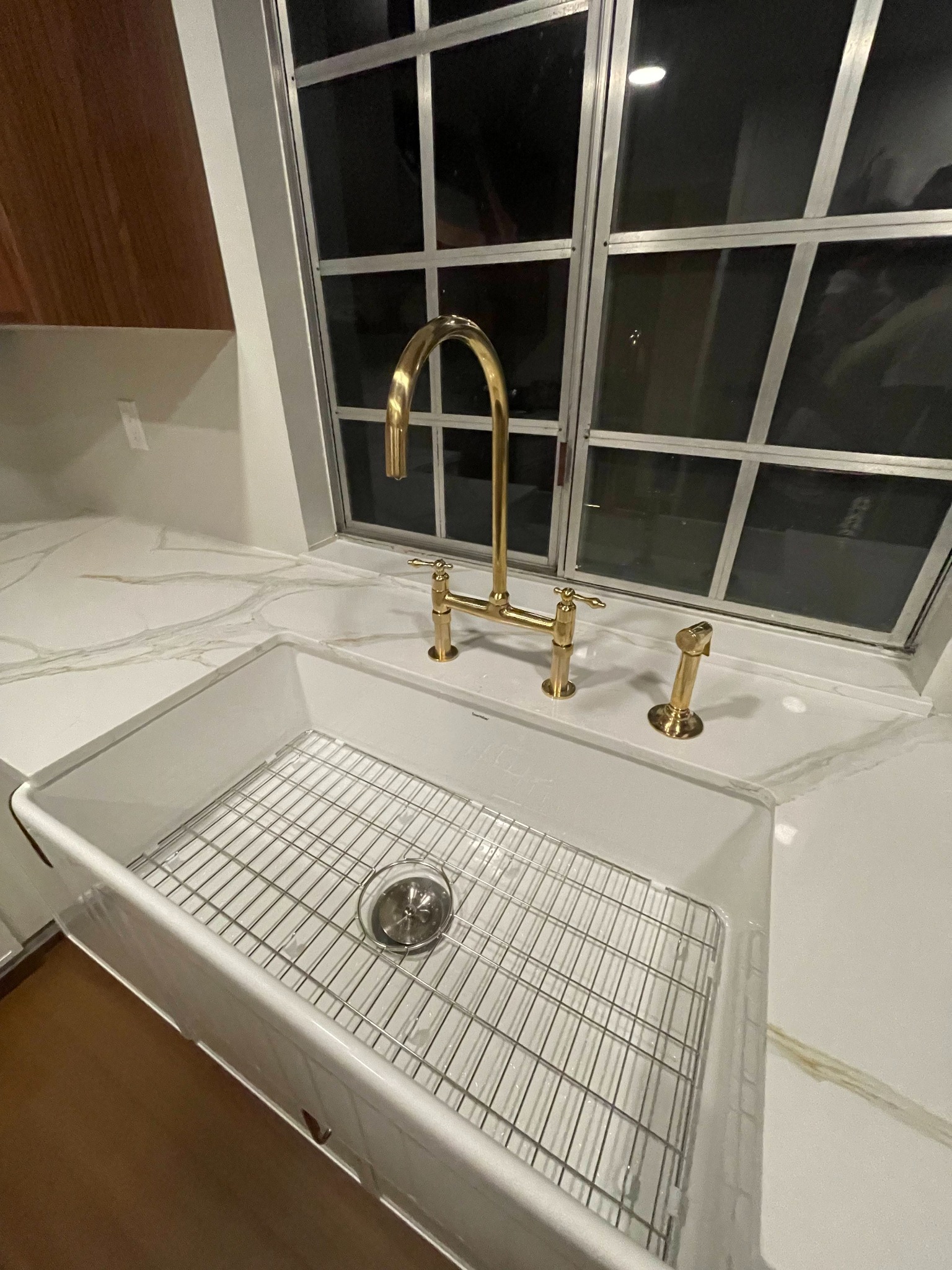 Installed brass kitchen faucet and farmhouse sink